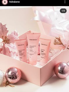 a pink box filled with different types of skin care products next to christmas ornaments and baubles