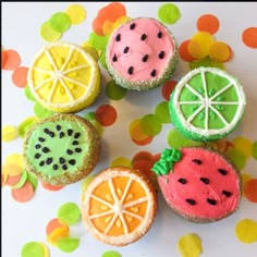 there are four decorated cookies with fruit on top of each cookie, one has a slice of watermelon and the other has an orange