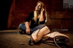 a woman sitting on the ground next to her shoes talking on a cell phone and looking up