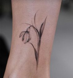 a small flower tattoo on the side of a woman's leg, it is black and white