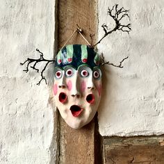 a mask hanging on the side of a building with eyes painted on it's face