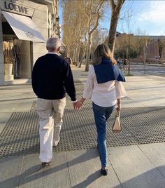 an older couple walking down the sidewalk holding hands