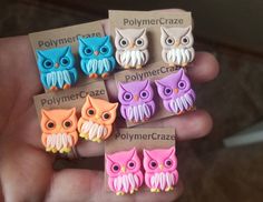 a person is holding some cute little owl earrings