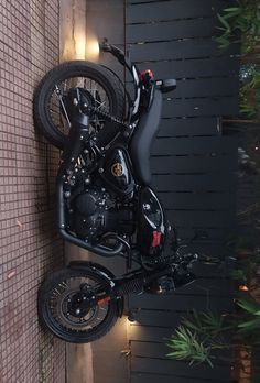 a black motorcycle parked on the side of a building next to a wall with lights