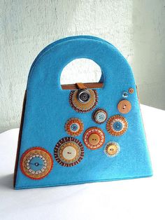 a blue purse with buttons on it sitting on top of a white table next to a wall