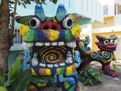 two colorfully painted statues next to each other in front of a tree and building