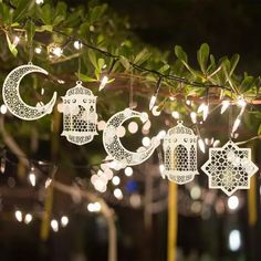 some lights are hanging from a tree with ornaments on it and in the shape of crescents