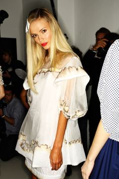 a woman with long blonde hair walking down a runway