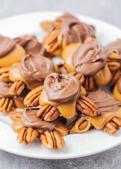 some pecans are covered in chocolate and caramel icing on a white plate