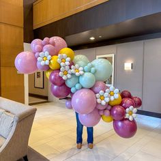 a woman standing in front of a lobby filled with lots of balloons and flowers on the ceiling