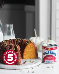 a cake on a plate next to a can of milk and pumpkins in the background