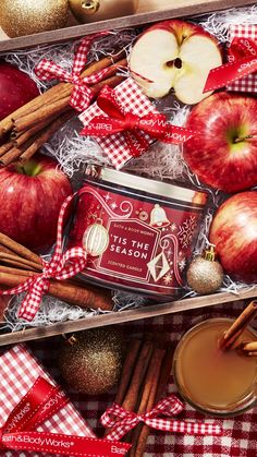 an apple cider and cinnamon sticks in a box with apples on the table next to it