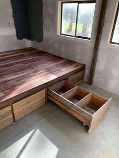 an unfinished bed frame with drawers on the bottom and sides, in a room under construction