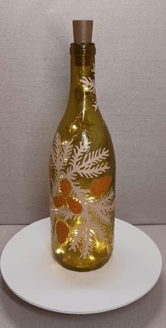 a glass bottle sitting on top of a white plate next to a gray wall behind it