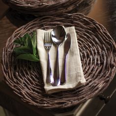 two forks and spoons sitting on top of a wicker tray with napkins