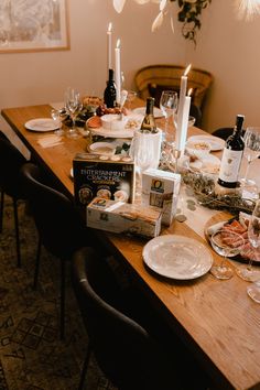 a dining table is set with wine, plates and candles for a festive dinner