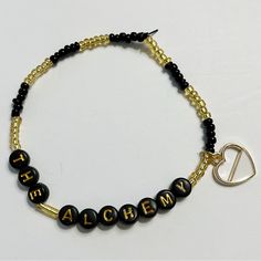 a black and gold beaded bracelet with the word alchem written on it