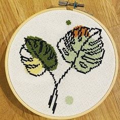 a cross - stitch pattern with a flower on the front and back of it, sitting on a wooden surface