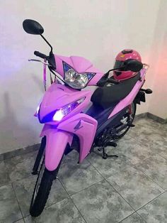 a purple motorcycle parked in a room next to a wall with a helmet on it