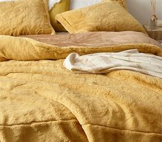 an unmade bed with yellow sheets and pillows