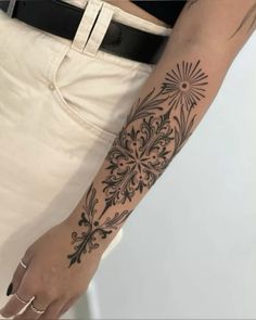 a woman's arm with a tattoo on it that has flowers and leaves in the middle