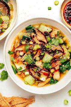 two bowls filled with soup and vegetables on top of a table