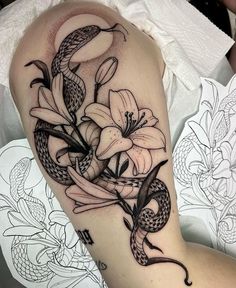 a woman's arm with a snake and flowers on it