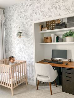 a baby in a crib next to a desk with a computer on it