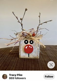 a vase with some branches in it and a face painted on the front, sitting on a table