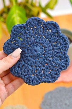 a hand holding a crocheted blue flower