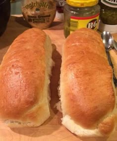 two long loafs of bread sitting on top of a cutting board next to some condiments