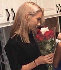 two women standing in a kitchen holding roses and looking at each other's eyes