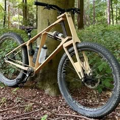 a wooden bicycle parked next to a tree in the woods