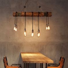 a wooden table and chairs with light bulbs hanging from the ceiling above it in an industrial style dining room