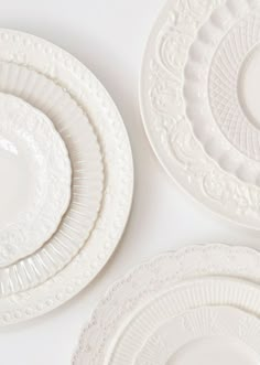 several white plates are stacked on top of each other, one is empty and the other has an ornate design