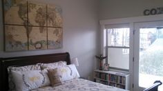 a bed sitting in a bedroom next to a book shelf and sliding glass door with a map on the wall