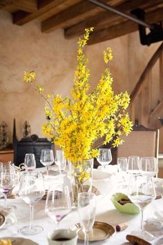 there is a vase with yellow flowers in it on top of the dining room table