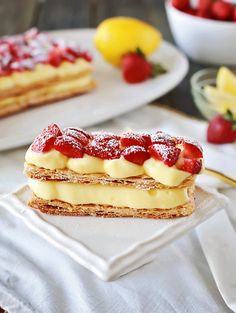 two desserts on plates with strawberries and lemons in the backgroud