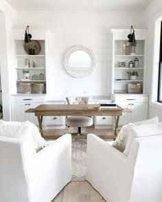 a living room with two white chairs and a table