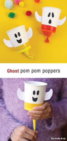 paper cups that look like ghost faces are being held by someone's hands with pom poms on them