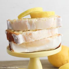 a cake with lemons and icing on a yellow plate next to some lemons