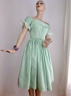 "Super Cute, 1950's ALL COTTON Mint Green Dress with a boxy square neckline & puffy lace sleeves. The neckline & lace sleeves gives this dress a mix between a baby doll dress and a German Fraulein maid dress.. The bodice is fitted with a nipped waist and series of cloth covered buttons up the front with a metal zipper down the back. The pleated skirt is full, and would flare out more with a petticoat. This comes with the original matching cloth covered belt. This dress is hand washable, Fitted Regency Style Vintage Dress For Vintage Fashion, Fitted Regency Style Vintage Dress, Regency Style Fitted Vintage Dress, Fitted Retro Vintage Dress With Square Neck, Vintage Dress With Square Neck, Tea Length Vintage Dress For Daywear, Vintage Formal Dress With Square Neck, Vintage Square Neck Dress For Garden Party, Retro Square Neck Dresses For Vintage Fashion