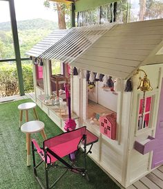 a doll house with furniture and accessories on the grass in front of windows overlooking trees