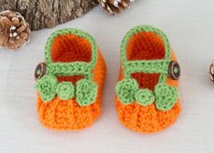 there is a pair of crocheted baby shoes next to pine cones