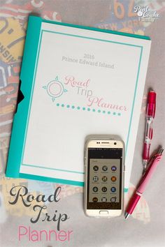 a cell phone sitting on top of a book next to a pen and paper with the words road trip planner