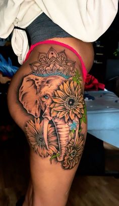 an elephant and sunflowers tattoo on the thigh