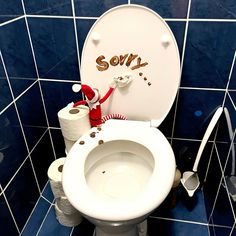 a white toilet sitting in a bathroom next to a roll of toilet paper with the word sorry written on it