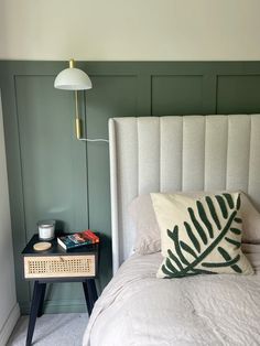 a bed with a white headboard and green walls