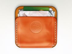 an orange leather wallet with money sticking out of it's front pocket on a white background