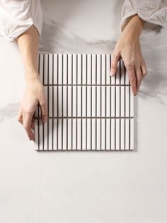 two hands on top of a white and black tile